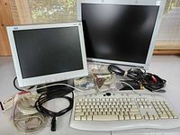 Two monitors, keyboard and bundled cables displayed