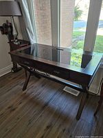 Three-quarter view of console table showing glass inset top and drawer front