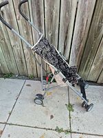 Side view of folded umbrella stroller showing frame, wheels and printed seat