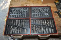 Both red metal cases open showing assorted drill bits arranged in size order