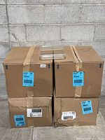 Four taped factory boxes stacked two by two with one clear clamshell container displayed on top