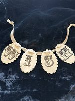 Front view of entire four-tag ceramic garland on ribbon