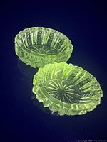 Two crystal salt cellars glowing green under UV light