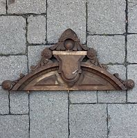 Full front view of carved wood pediment showing overall design and wear
