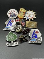 Overview of all twelve enamel pins on black background