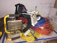 Overview photo showing the Craftsman wet dry vac, multiple coiled extension cords in different colors, and a yellow work light with metal frame.