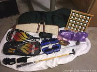 Full lot includes two racket ball rackets, jump ropes, ankle weights, wooden golf ball display, golf bag, gun case, TaylorMade golf driver, and Momentus putter.
