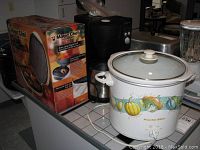 Proctor Silex slow cooker with vegetable design, Capresso 471 coffee maker, and Magic Chef grill box on countertop.
