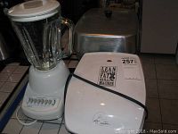 Full lot showing Hamilton Beach blender, George Foreman grill, Presto electric fry pan, and West Bend slow cooker.