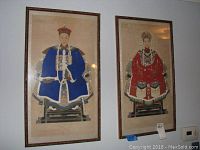 Two framed Chinese ancestor portrait prints on silk hanging on a wall, showing male and female figures in traditional attire.