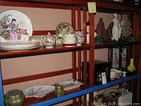 Two shelves showing decorative plates, bowls and small items