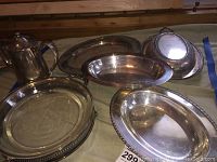 Photo showing the coffee pot, multiple silver plated trays including oval and round trays, and the divided dish with engraved lid.
