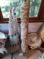 Photo showing both folded hammocks hanging side by side next to a wooden post and hat.
