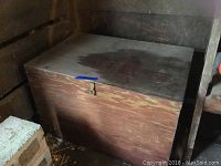 Full view of rectangular wooden box with lid closed, showing visible wear, scratches, and water stains on top surface.