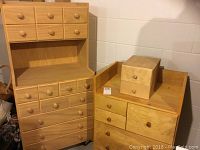Overall view of two handmade wooden kids storage cabinets side by side, showing drawer fronts and knobs.