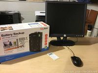 Photo of Cyber Power battery backup box, Dell 17 inch computer monitor with stand and mouse on desk.