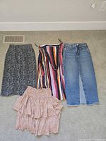 All four skirts laid flat: black snakeskin knit, striped wrap, blue denim, pink tiered
