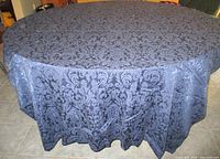 Full view of tablecloth draped over round table showing overall floral damask pattern