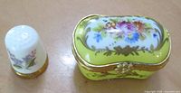 Pill box and thimble side by side showing scale and decoration
