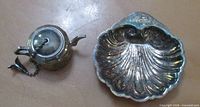 Scallop shell dish and teapot-shaped tea strainer side by side