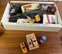 Box containing track sections, controllers, power pack, accessory box; four cars displayed