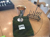 Sterling silver goblet standing on a green cloth on a wooden table with an auction card in front.