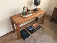 Full view of the wood side table with decorative items on top and books underneath showing size and design.