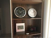 Shelf with two analog clocks and two digital clocks, wooden background