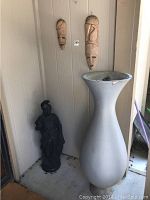 Lot including concrete Trojan statue, two wooden masks mounted on wall, large resin vase on floor.