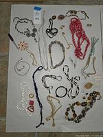 Entire lot laid out showing variety of necklaces, bracelets, earrings, rings and brooches