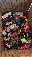 Box filled with assorted 1:64 die-cast toy cars