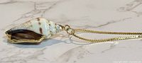 Close-up of shell pendant showing colors and gold-tone edging
