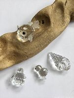 Group of four Swarovski crystal figurines on driftwood: fish, penguin, chick, seashell