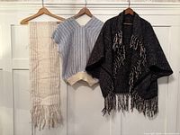 White-beige scarf, blue vest, black poncho on hangers