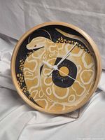 Full view of round snake motif wall clock with wood frame