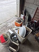 Overview of buckets and bin with assorted scrap metal pieces near garage opening