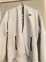 Front view light gray Nike Tech half-zip hoodie showing pockets and logo