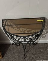 Front view of demilune console table showing iron scrollwork and glass top