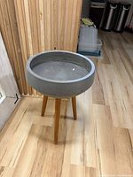Full view of gray plaster planter on three wooden legs