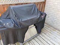 Grill fully covered with black cover on deck