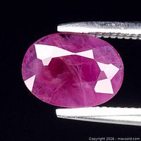 Front view of oval purplish-red ruby held in tweezers