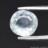 Front view of cushion-cut light bluish green tourmaline held by tweezers