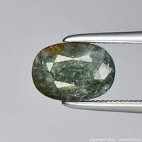 Oval green tourmaline gemstone held by tweezers