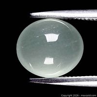 Oval cabochon translucent pale bluish green beryl held in tweezers, showing overall shape, color and clarity