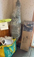 Wrapped 70" tree, box with stand parts, bag with decor visible
