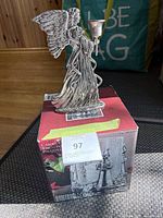 Angel candlestick atop boxed hurricane candle holder