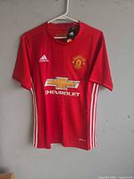 Front view of Adidas Manchester United jersey on hanger showing overall design