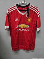 Front view of red Adidas Manchester United jersey on hanger