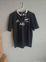 Front view of black Adidas All Blacks jersey on hanger