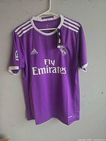 Front view of purple Real Madrid Adidas jersey hanging
